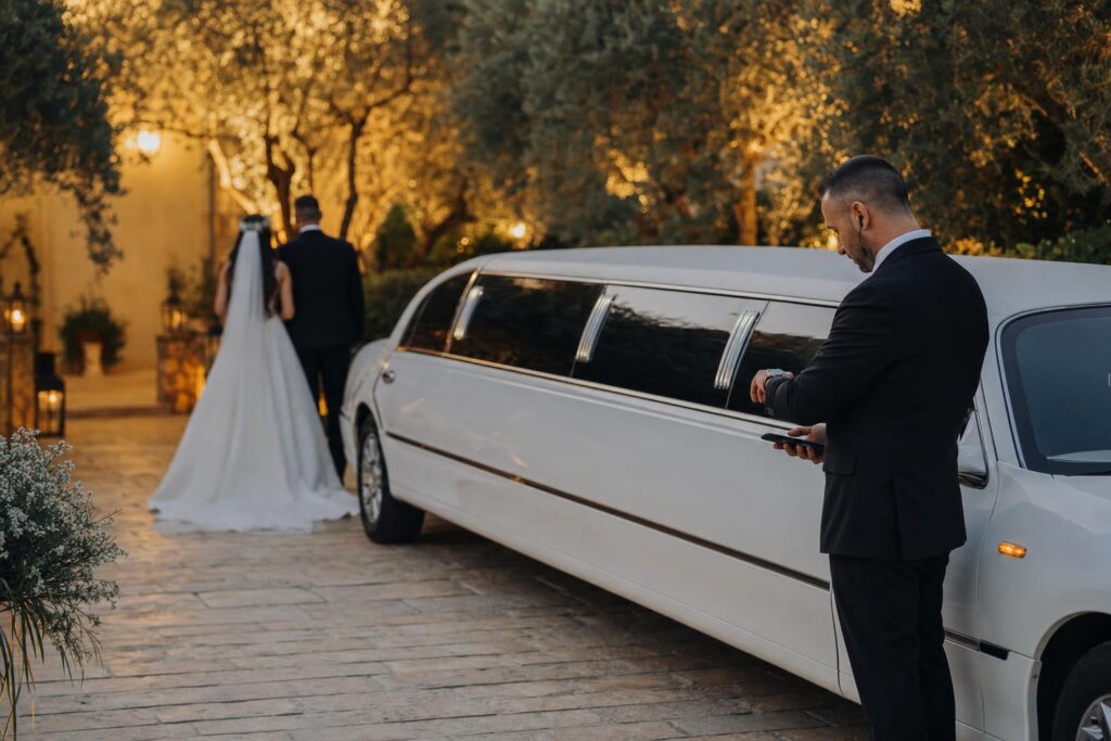 לימוזינה לבנה ליד גן אירועים עם נהג שבודק זמני הגעה, המחשה לשאלה מה קורה אם הלימוזינה מאחרת